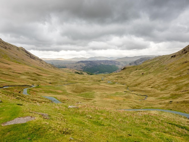 Vista del paisaje rural de campo verde y fondo de montaña bajo un cielo nublado en Inglaterra