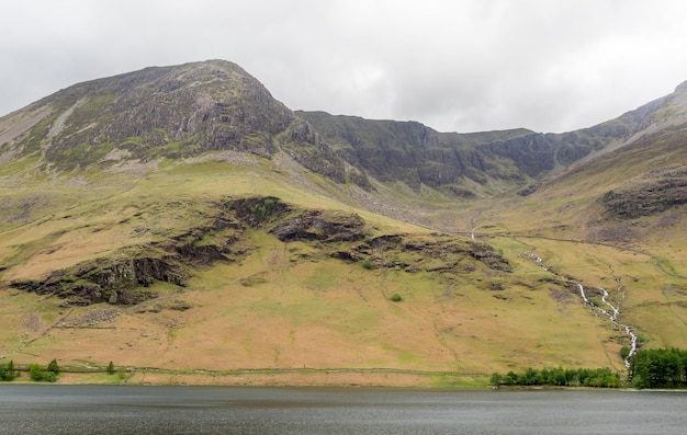 Vista del paisaje rural de campo verde y fondo de montaña bajo un cielo nublado en Inglaterra