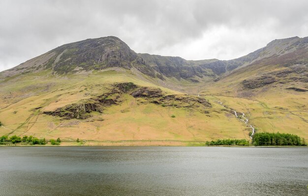 Vista del paisaje rural de campo verde y fondo de montaña bajo un cielo nublado en Inglaterra