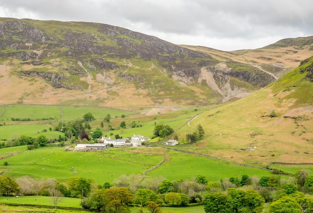 Vista del paisaje rural de campo verde y fondo de montaña bajo un cielo nublado en Inglaterra