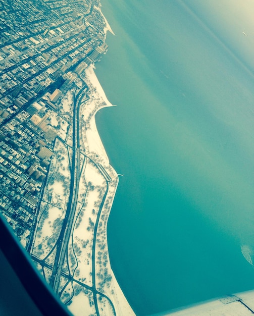 Foto vista del paisaje urbano y el océano desde la ventana de un avión