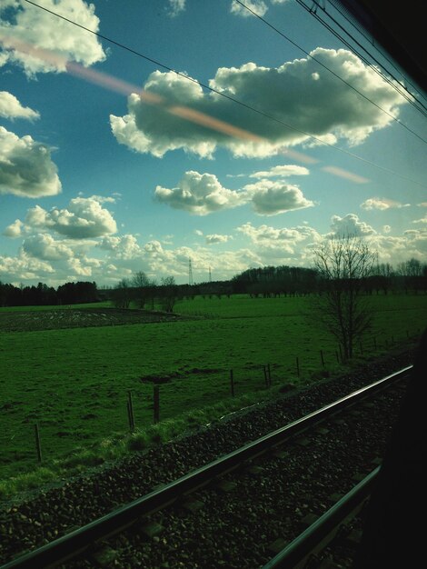 Vista del paisaje verde contra el cielo nublado vista desde la ventana del tren