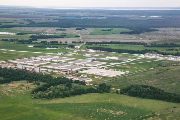 Vista de pájaro de edificios industriales entre campos verdes