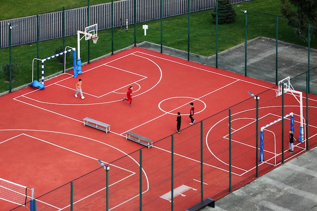 Foto vista de pájaro en el patio de juegos de baloncesto con algunos niños jugando con la pelota.