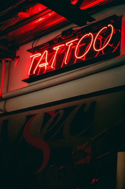 Vista de la palabra tatuaje con luz roja de neón en el edificio