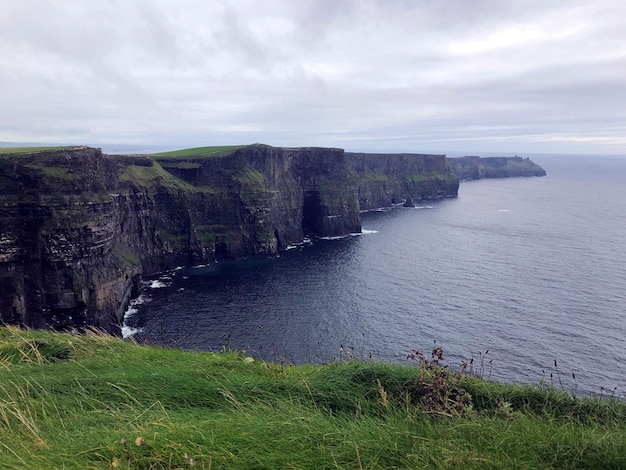 Foto vista panorámica de los acantilados de moher. impresionante paisaje irlandés con el océano atlántico, altos acantilados y hierba