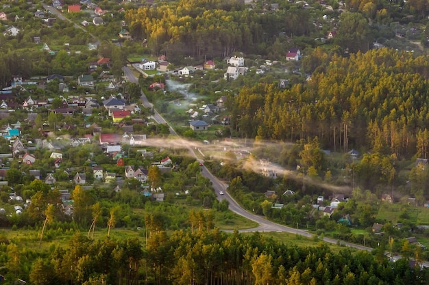 Vista panorâmica aérea da aldeia verde com casas celeiros e estrada de cascalho na floresta