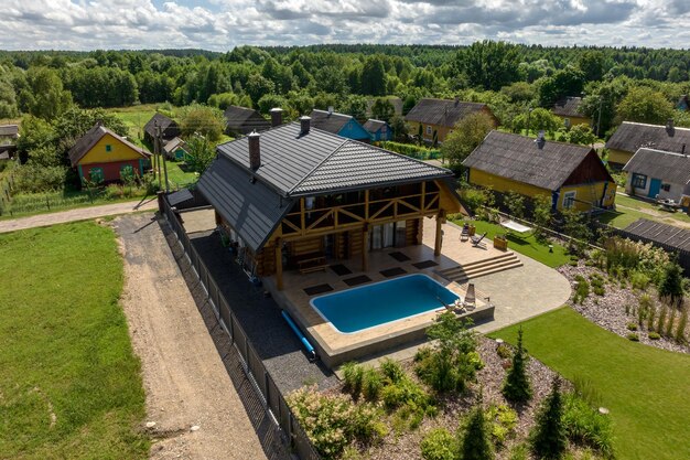 Vista panorâmica aérea na casa ecológica de madeira ou herdade com piscina na aldeia verde