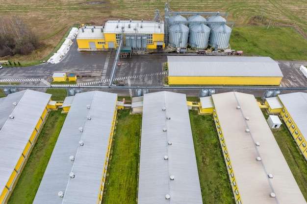 Vista panorámica aérea sobre los silos y el complejo ganadero agroindustrial en la planta de agroprocesamiento y fabricación con hileras modernas de granja de pollos con elevador de granero de gallinero