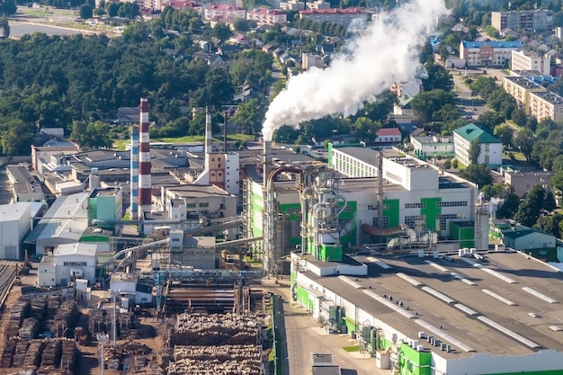 Vista panorámica aérea sobre tubos de humo de una fábrica de carpintería en la orilla de un río ancho