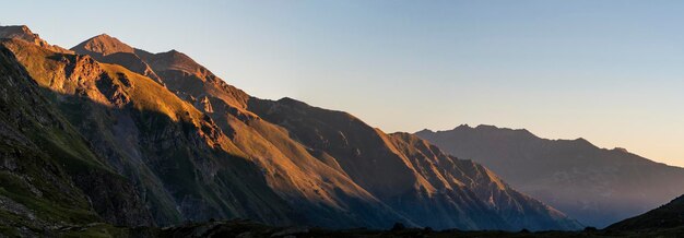 Vista panorámica del amanecer dorado en montañas con fondo de cielo despejado