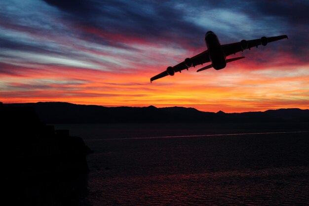 Vista panorámica del amanecer sobre las montañas con avión sobre el mar