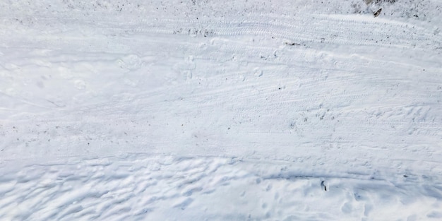 Vista panorámica desde arriba sobre la textura de la carretera cubierta de nieve con huellas y huellas de neumáticos de automóviles