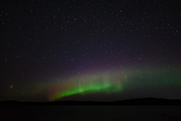 Vista panorámica de la aurora boreal. Luces polares en el cielo estrellado de la noche sobre el lago.