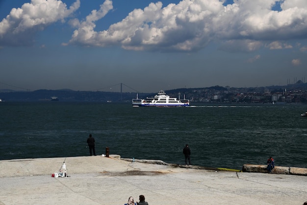 Foto vista panorámica del bósforo hay un ferry que cruza el estrecho la gente está pescando en la orilla 11 de abril de 2022 estambul turquía