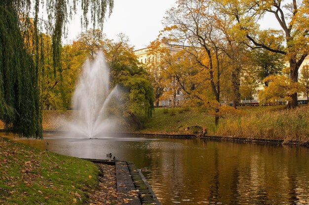 Una vista panorámica de un canal de agua en un parque en el centro de Riga con árboles amarillos y rojos