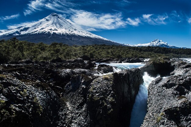 Foto vista panorámica de la cascada contra las montañas cubiertas de nieve