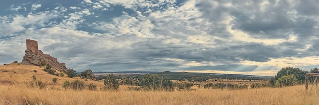 Vista panorámica de un castillo medieval en la cima de una colina y los rayos del sol a través de las nubes