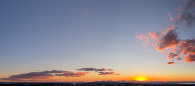 Vista panorámica de la ciudad, el océano y la montaña al atardecer.