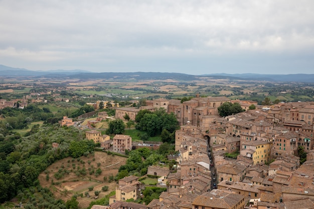 Vista panorámica de la ciudad de Siena con edificios históricos y lejanos campos verdes de Torre del Mangia es una torre en la ciudad. Día soleado de verano y espectacular cielo azul