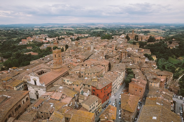 Vista panorámica de la ciudad de Siena con edificios históricos y lejanos campos verdes de Torre del Mangia es una torre en la ciudad. Día soleado de verano y espectacular cielo azul