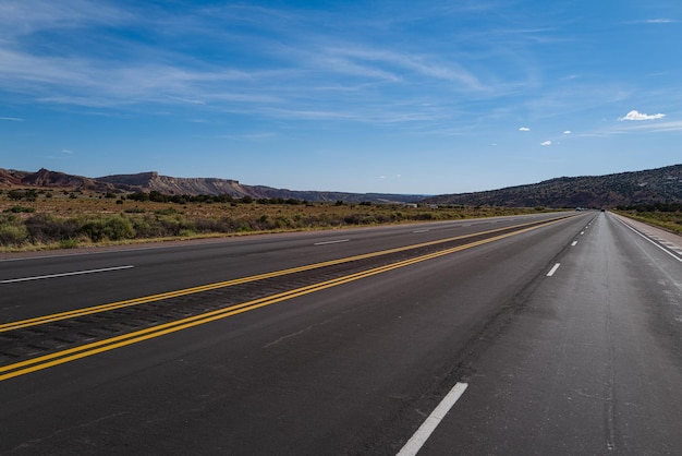 Vista panorâmica clássica de uma estrada reta sem fim que atravessa o cenário estéril do americano