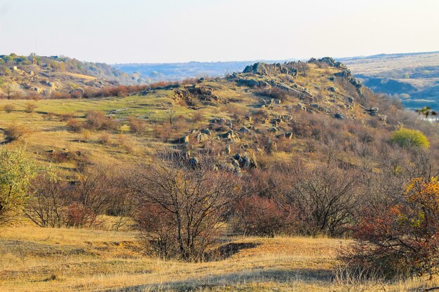 Vista panorámica de colinas rocosas, prados y árboles en otoño