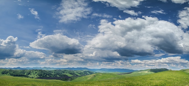 Vista panorámica de colinas verdes y pintoresco cielo azul con nubes blancas