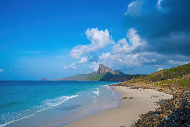 Vista panorámica costera de la isla de Con Dao desde arriba con olas costa cielo despejado y camino azul mar y montaña Vista aérea de la playa de Bai Nhat con día nublado Concepto de viaje