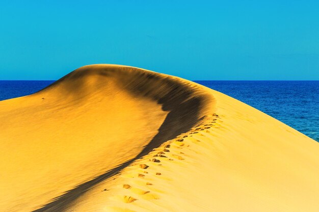 Foto vista panorámica de la curva de la duna de arena contra el cielo azul claro en maspalomas