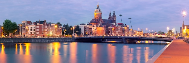 Vista panorâmica da cidade à noite do canal de Amsterdã, da ponte e da Basílica de São Nicolau, Holanda, Holanda. Exposição longa. Tonificação usada