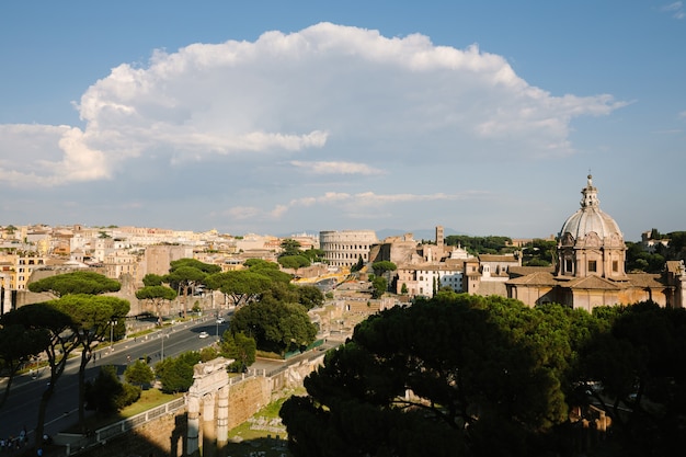 Vista panorâmica da cidade de roma com o fórum romano e o coliseu do monumento vittorio emanuele ii, também conhecido como vittoriano. dia ensolarado de verão e céu azul dramático