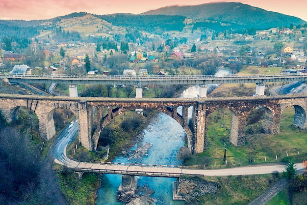 Foto vista panorâmica da cidade de vorokhta no vale da montanha três pontes sobre o rio prut vista da ponte rodoviária e duas pontes ferroviárias