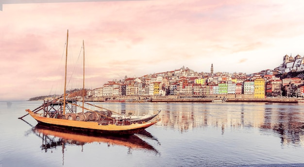 Foto vista panorâmica da cidade velha do porto barco rabelo em primeiro plano no rio douro porto portugal