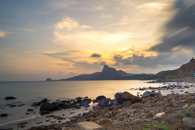 Vista panorâmica da ilha costeira de Con Dao de cima com ondas, litoral, céu claro e estrada, mar azul e montanha Vista aérea da praia de Bai Nhat com pôr do sol cinematográfico