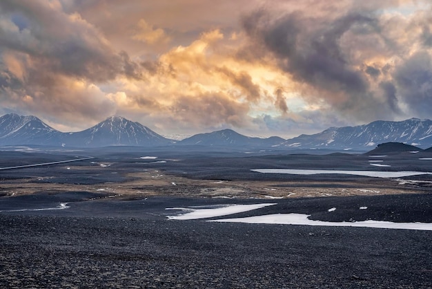 Vista panorâmica da neve na paisagem vulcânica contra montanhas durante o pôr do sol