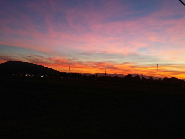 Vista panorâmica da paisagem de silhueta contra o céu nublado durante o pôr-do-sol