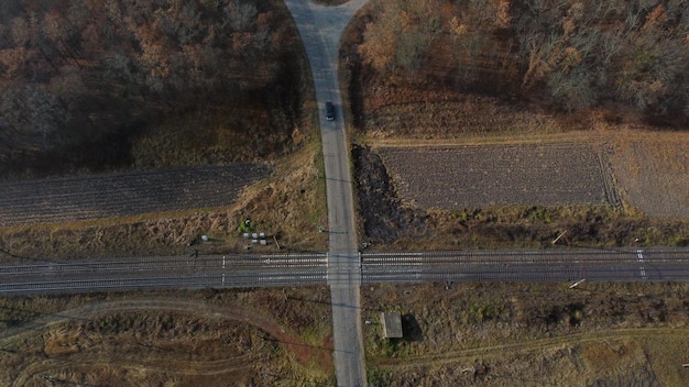 Vista panorâmica da travessia ferroviária entre árvores em campos de visão aérea de drones