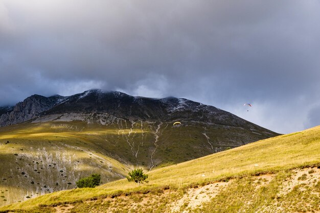 Foto vista panorâmica das montanhas contra o céu com parapente em castelluccio umbria, itália
