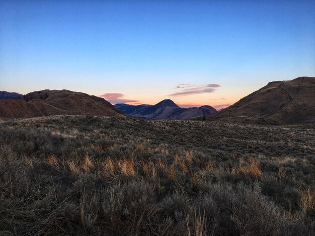 Vista panorâmica de campos e montanhas contra um céu azul claro