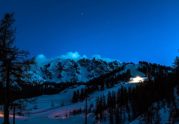 Foto vista panorâmica de montanhas cobertas de neve contra o céu azul à noite