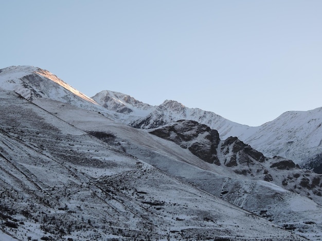 Foto vista panorâmica de montanhas cobertas de neve contra o céu claro kabardino balkaria eltyubu cidade dos mortos