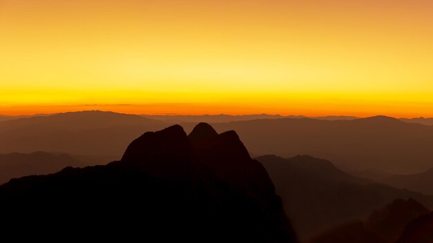 Foto vista panorâmica de montanhas em silhueta contra o céu laranja