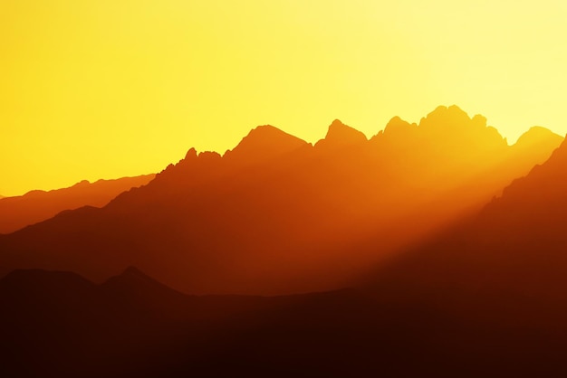 Vista panorâmica de montanhas em silhueta contra o céu laranja