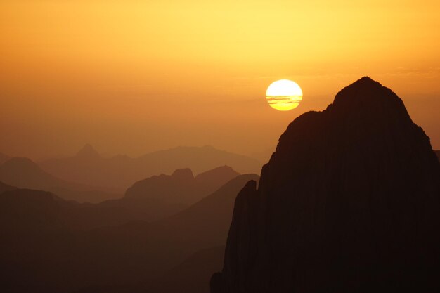 Foto vista panorâmica de montanhas em silhueta contra o céu laranja