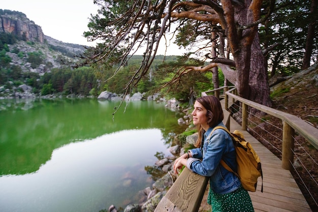 Foto vista panorâmica de mulher caucasiana, turismo em caminho isolado com mochila. visão horizontal de mulher viajando sozinha na lagoa negra em soria. pessoas e destinos de viagens na espanha.