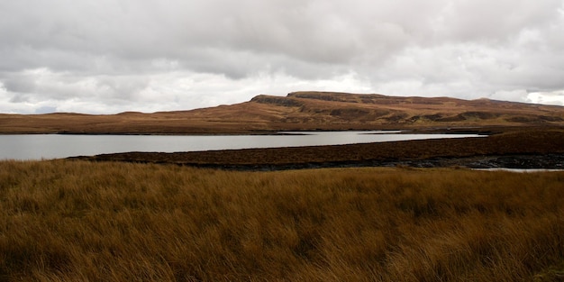 Vista panorâmica de um campo ao lado de um lago contra um céu nublado