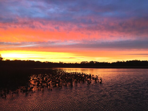 Foto vista panorâmica de um lago calmo contra um céu dramático durante o pôr-do-sol