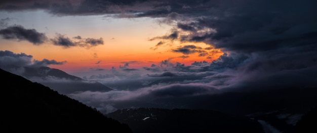 Vista panorâmica do céu dramático com nuvens escuras de tempestade no fundo do sol vermelho e laranja