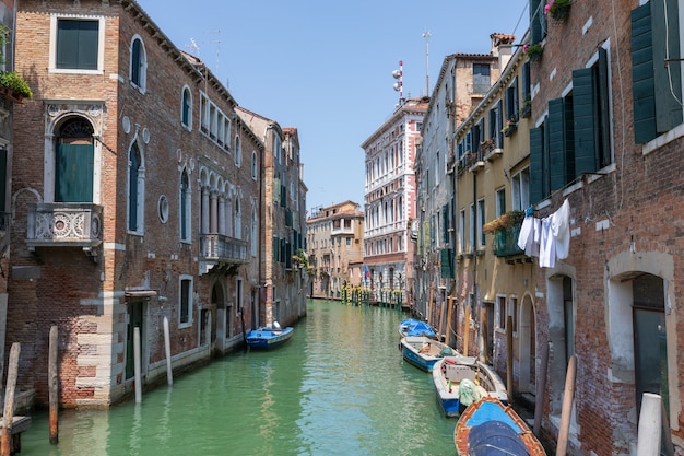 Vista panorâmica do estreito canal de Veneza com edifícios históricos e barco da ponte. Paisagem de dia ensolarado de verão